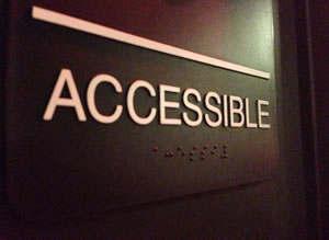 サンプル：ドアに並記されているアルファベットの大文字「ACCESSIBLE」の凸文字と点字の写真